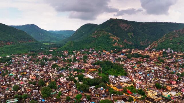 Drone view of Alwar city roads, greenery, and Aravalli mountains in the background.