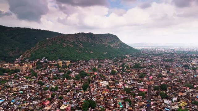 Cinematic drone view of Alwar city with green landscapes and Aravalli mountain backdrop.