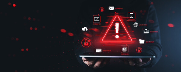 Cybersecurity alert warning triangle with digital danger icons hovering above tablet in hands on...