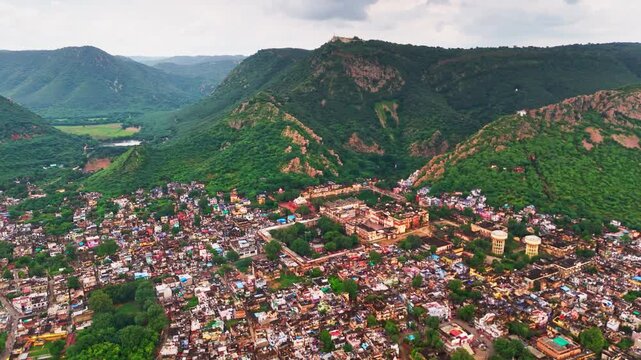 Drone view of Alwar city showing scattered houses, greenery, and the Aravalli hills forming a soft natural frame behind the skyline.