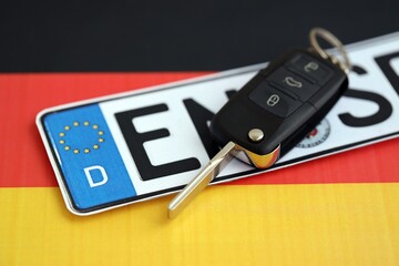 Germany Deutschland car license plate and key on german flag close up. Driving permit and...