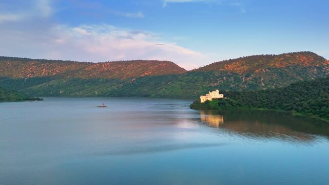 A wide evening drone shot of Siliserh Lake in Alwar capturing soft sunset colors, still water, and the natural beauty of Rajasthan. Calm, cinematic, and visually soothing.