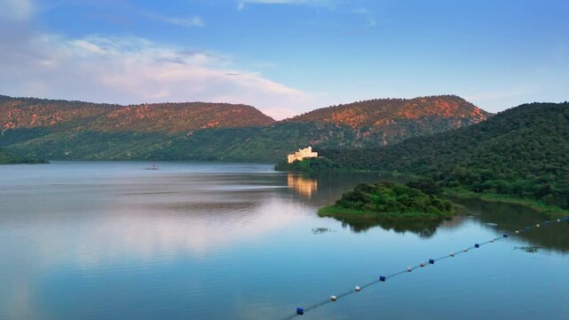 Evening drone view of Siliserh Lake in Alwar, Rajasthan, showing golden light on calm water, soft reflections, and peaceful natural surroundings. A beautiful scenic moment from the heart of Rajasthan.