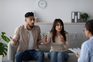 Young Arab couple in a counseling session express strong emotions while discussing their relationship problems with a therapist in a comfortable office setting.