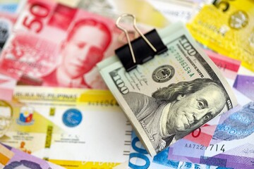 Philippines peso currency money bills and bunch of us dollar banknotes close up. The concept of economics and currency exchange