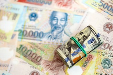 Vietnamese dong currency money bills and bunch of us dollar banknotes close up. The concept of economics and currency exchange