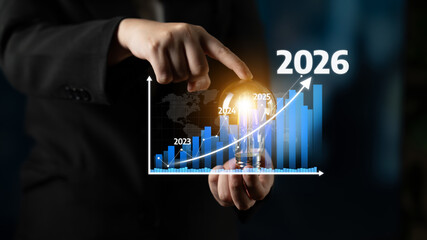 A businessman holds a light bulb while pointing at a growing graph. This image symbolizes innovation, investment projections, and business success for the future. Tessel