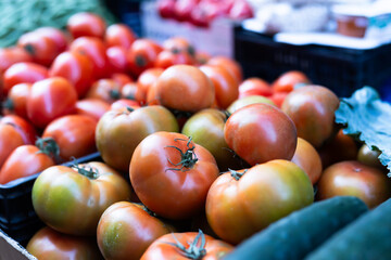 Different of ripe tomatoes offered for sale on counter of local vegetable market