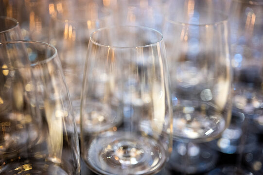 Rows of empty clean wine glasses with shining bokeh. Close-up of crystal goblets background. Catering service concept for wedding reception, restaurant or banquet event, selective focus, defocus, back