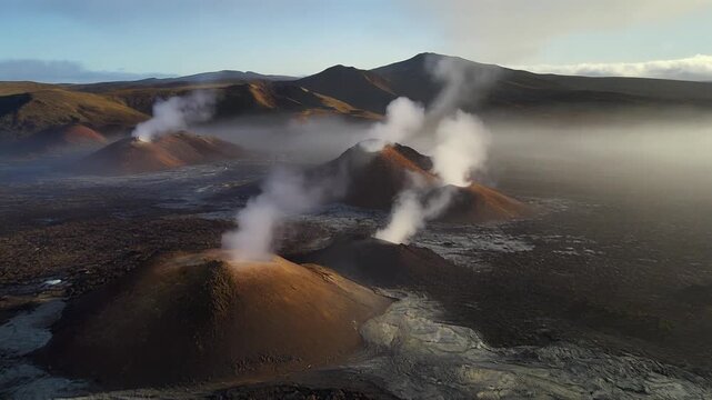 Morning haze softens a chain of volcanic ridges with faint fumaroles rising from scattered vents along the rugged terrain