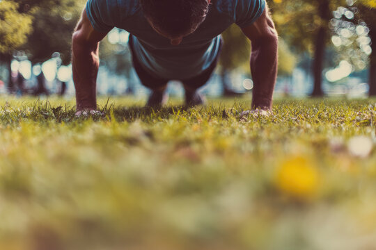Man exercising outdoors push up on grass blurred background strong arms fitness training healthy lifestyle summer park determination workout motivation natural light