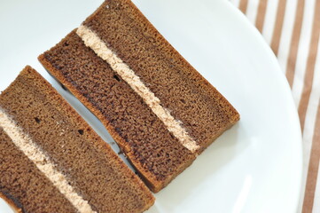 Two rectangular slices of chocolate sponge cake are shown on a white plate