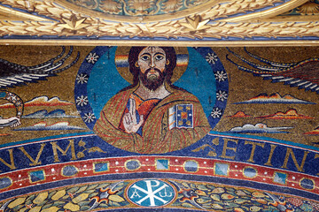 San Clemente Basilica.   Apse mosaic.  Medieval mosaic bust of Christ with benediction gesture and jeweled book above decorative frieze.