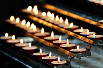 San Clemente Basilica.  Rows of votive tealight candles flicker in a church, soft glow illuminating prayerful silence.