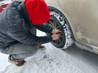Man Inflating Car Tire in Snowy Winter Weather