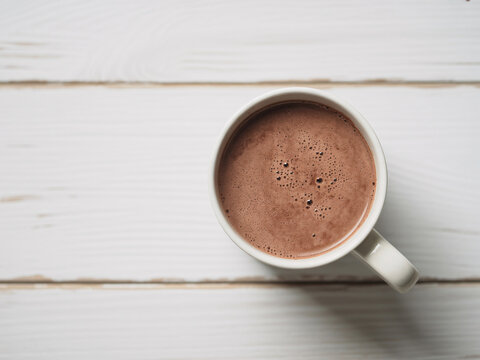 Indulge in the creamy delight of a hot chocolate, perfect for cozy mornings and comforting moments on a rustic white table backdrop