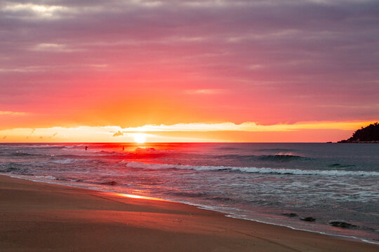 Sunrise on Campeche beach in contrast with people near the sun in Florianopolis, Santa Catarina, Brazil.