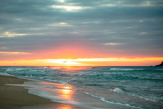 Sunrise on Campeche beach in contrast with people near the sun in Florianopolis, Santa Catarina, Brazil.