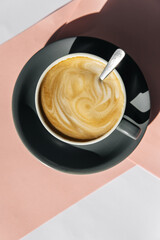 Latte art in a glass on a pinkish-gray background