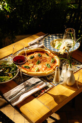 Table setting for dinner in Italy. Pizza, pasta, wine and salad