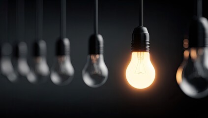 One glowing light bulb stands out in a row of dim bulbs on a dark background