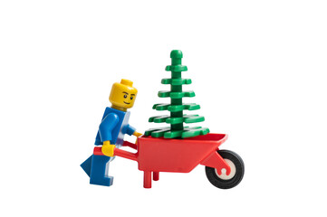 Obraz premium Lego man pushing a wheelbarrow with Christmas tree. Studio shot.