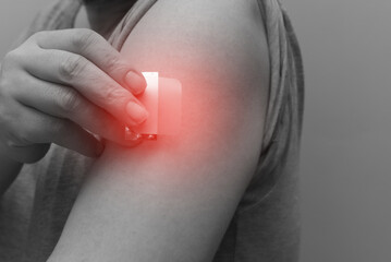 A close-up of a hand applying a nicotine patch to the upper arm. Represents Nicotine Replacement Therapy (NRT) and the user's commitment to quit smoking and pursue better health