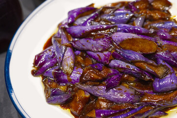 glossy slices of purple eggplant (aubergine) stir-fried and braised in a savory brown sauce (soy or garlic sauce). The vibrant colors represent a flavorful Chinese or Asian vegetable side dish