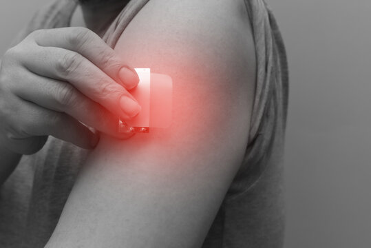 A close-up of a hand applying a nicotine patch to the upper arm. Represents Nicotine Replacement Therapy (NRT) and the user's commitment to quit smoking and pursue better health