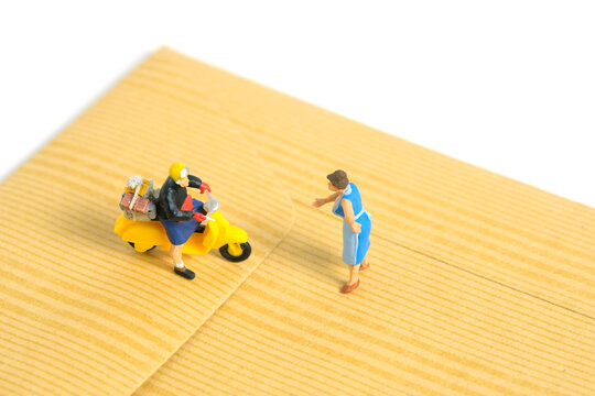 Miniature people toys conceptual photography. Mail postal courier delivery. Postman courier with envelope, isolated on white background.