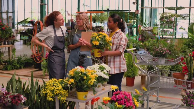 Diverse group of people, including a male florist, a female manager, and a young customer, talking and choosing yellow potted flowers together inside a bustling and vibrant garden center - Powered by Adobe