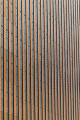 A striped brown bamboo mat texture on an old brick wall creates a natural wooden surface pattern background