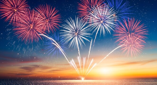 Spectacular fireworks burst in brilliant red white and blue over a vibrant sunset ocean horizon celebrating a holiday or anniversary event at night