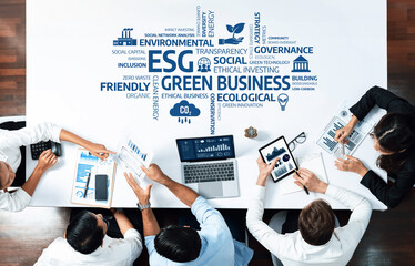 A top view of a diverse business team discussing strategies for green practices and sustainability, using data analysis and reports for informed decision-making. Amity