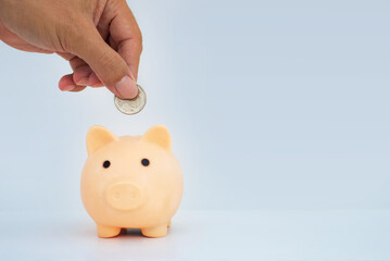 money saving concept. business man han dropped coin on piggy bank with coin stack on dark blue background. money matters tips to investment and business financial banking for Financial Wellness.