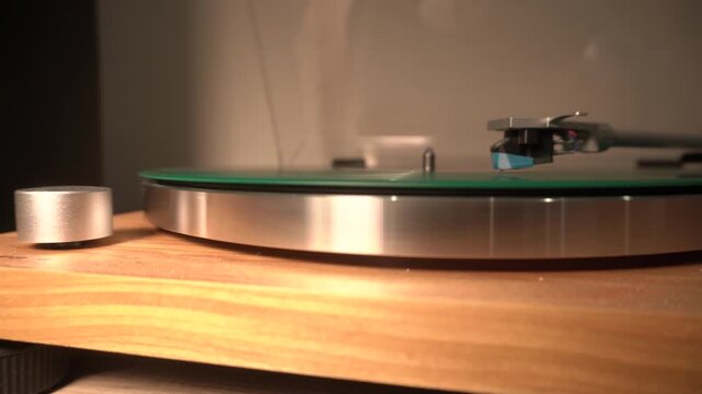 new green music plate is installed in the media player. music is played with a needle. general shot, yellow lamp light. on the left is the volume relay. transparent cover open,focus on the needle