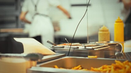 A close-up view of French fries in an industrial kitchen, highlighting the display case where staff prepare quick snacks for customers during busy hours