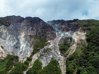 A volcanic mountain slope with exposed geothermal rocks and erosion patterns seen from above aerial