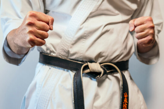 Martial artist showing clenched fists near black belt.