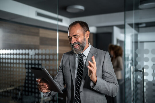 Mature businessman waving during video call using tablet