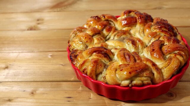 Left to right video shot of freshly baked rustic homemade cinnamon rolls from yeast dough on wooden table