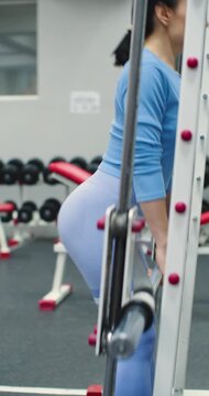 Smith machine barbell curls. Leg and glute workout. Deadlift workout. Focused Smith machine barbell curls build arm strength during a dynamic gym session. Slow motion 4k vertical footage.