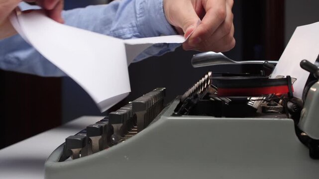Hands tear a sheet of paper from an old manual typewriter, symbolizing writer's block, frustration, and a need for new ideas during the creative writing process
