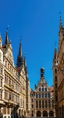 Fototapeta premium Historic central European plaza building featuring ornate stone facades and classic tall spires against a clear blue sky ,Architecture ,old ,ornate stone