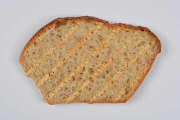 A single slice of lightly toasted bread featuring distinct grill marks rests on a plain white background.
