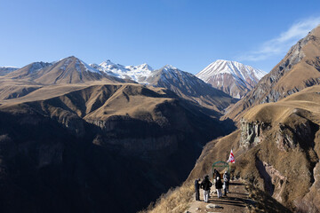 Kazbegi, Georgia - November 03, 2025: Group of hikers exploring stunning mountain landscape in Georgia, with snow-capped peaks and clear blue sky, showcasing the beauty of nature and adventure