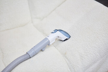 Vacuum cleaner on the white sofa. 