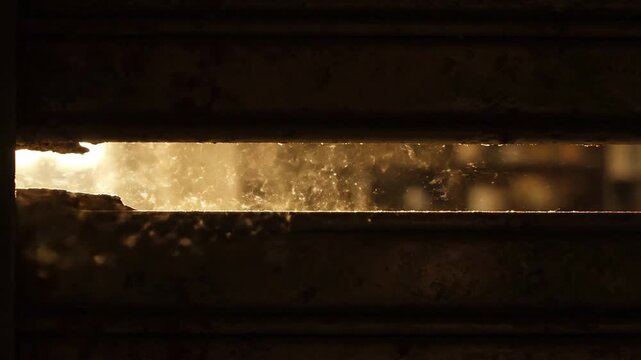 Damaged metal shutter, light peeking through a gap in the slats