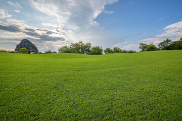 Rolling green grass hills and mountain landscape under dramatic cloudy sky.