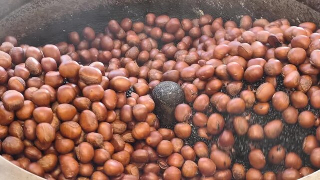Close Up view of cooking chestnuts in a roasting machine at a food market